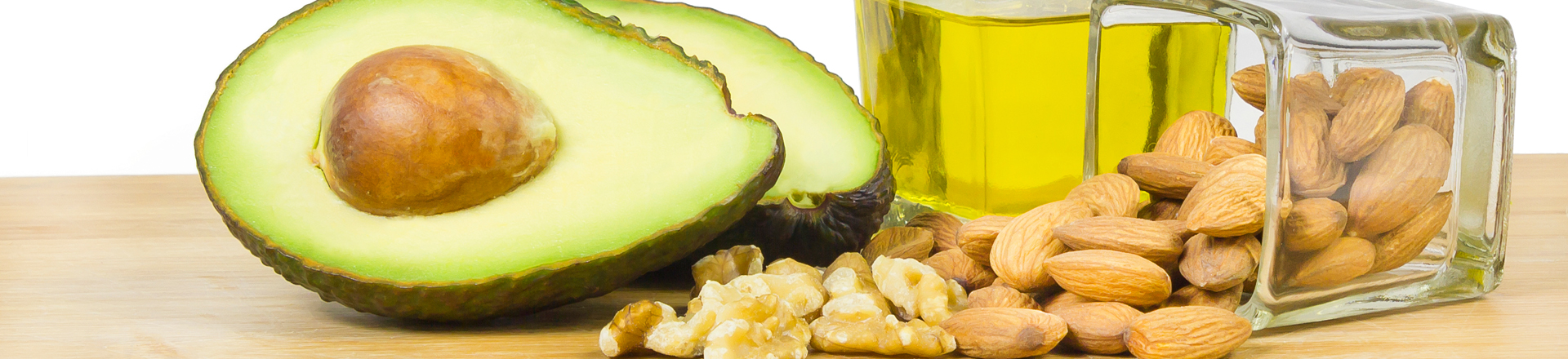 healthy monounsaturated fats olive oil, avocado, and walnuts, and almonds - on a cutting board