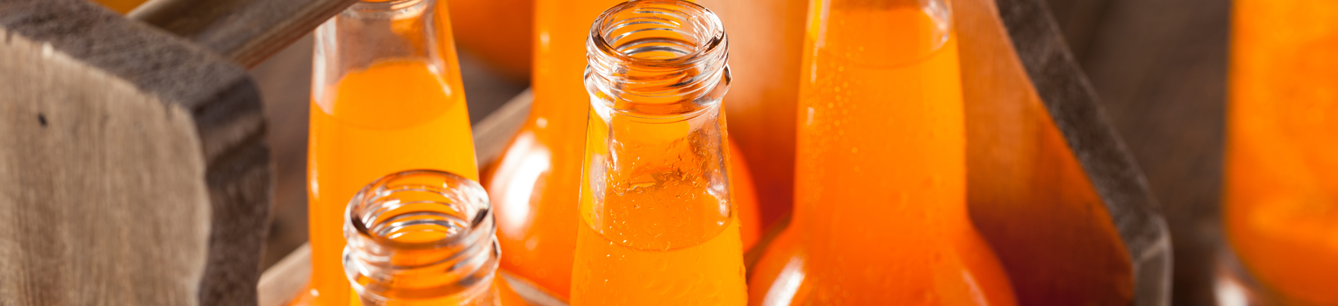 long neck glass orange soda bottles in a wooden case