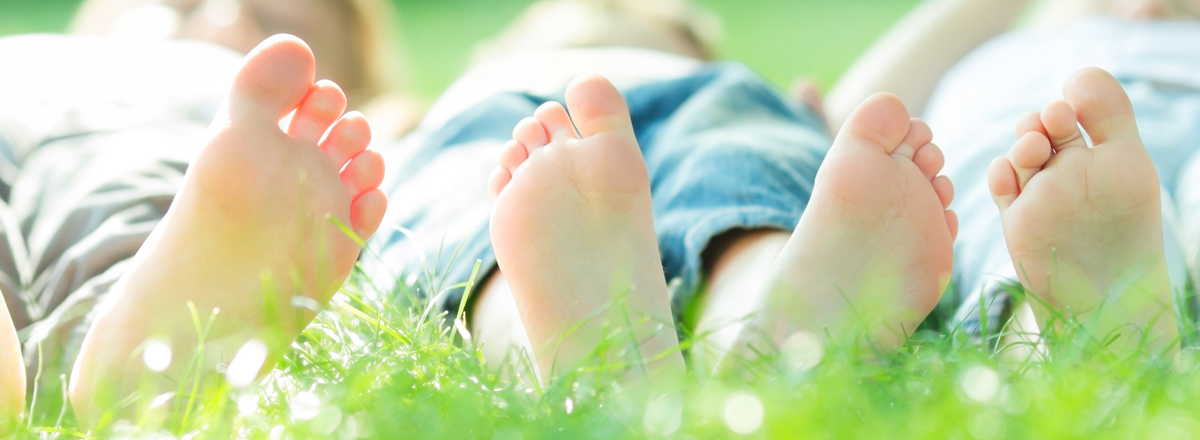 children lay in the grass earthing with barefeet