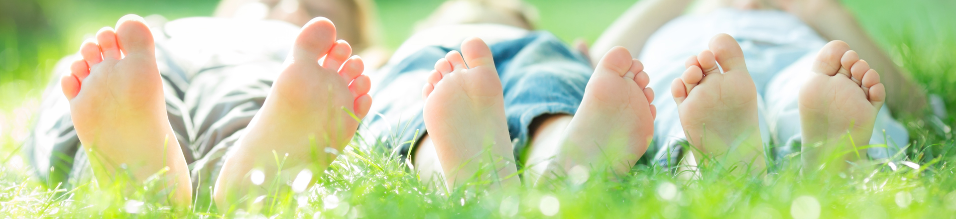 children lay in the grass earthing with barefeet