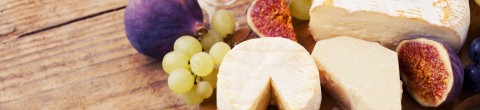 cutting board with fruits and rounds of cheese