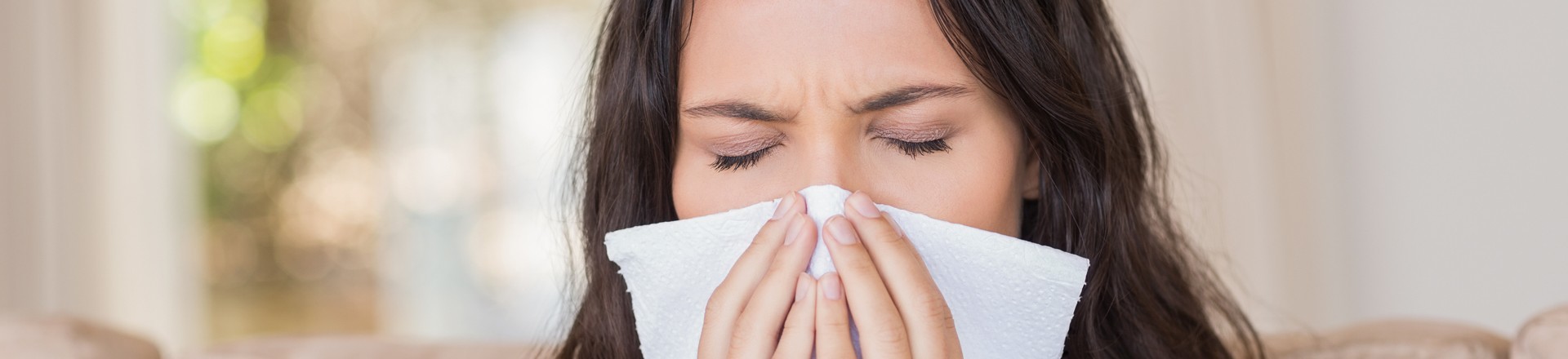woman with allergies blowing her nose with a tissue