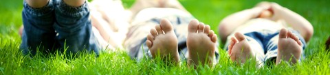 three kids laying in the grass with barefeet