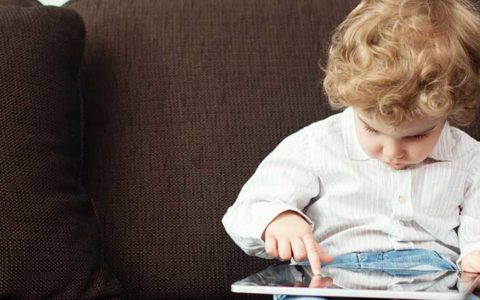 small boy with laptop on lap faces potential wifi dangers