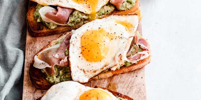 Avocado toast with fried egg, prosciutto, and jalapeno garlic olive oil