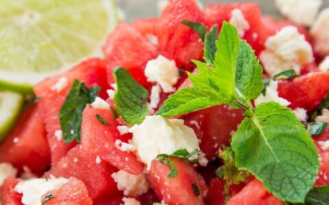 watermelon salad with feta cheese and mint, garnished with lime wheels.