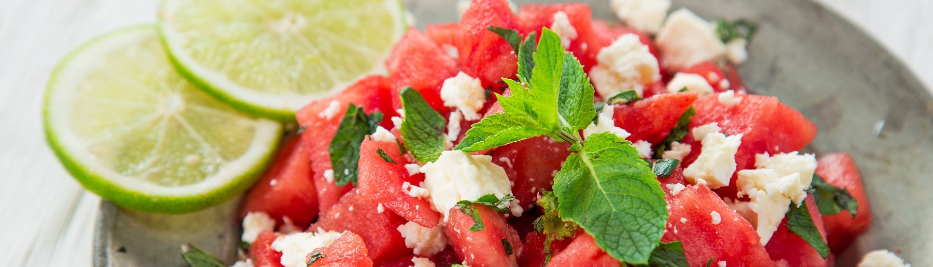 watermelon salad with feta cheese and mint, garnished with lime wheels.